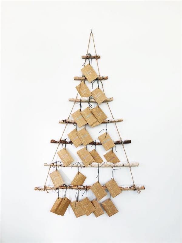 Advento kalendorius, pagamintas iš dreifuojančių medžių šakų ir vielos ant baltos sienos su mažomis pakuotėmis, originalus dovanų įpakavimas senoviniame laikraštyje