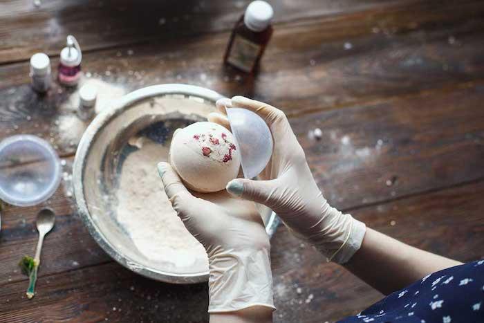 ženska iz svoje kozmetike izdeluje kopalne kroglice z okroglim kalupom
