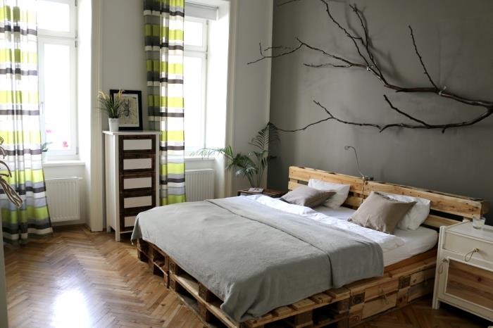 Vzglavje palete DIY, soba s sivimi stenami in lesenimi tlemi z dolgimi zelenimi in rjavimi zavesami