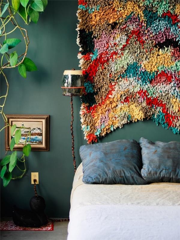 Vzglavnik DIY v večbarvni preprogi, smaragdna črvasta stena, modre blazine in belo posteljnina, zelena rastlina