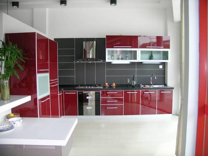 bordo rdeča kuhinjska sprednja stran s sivim škropljenjem, sesalnik iz nerjavečega jekla, majhen siv otok z belo delovno ploščo, umazano bela tla
