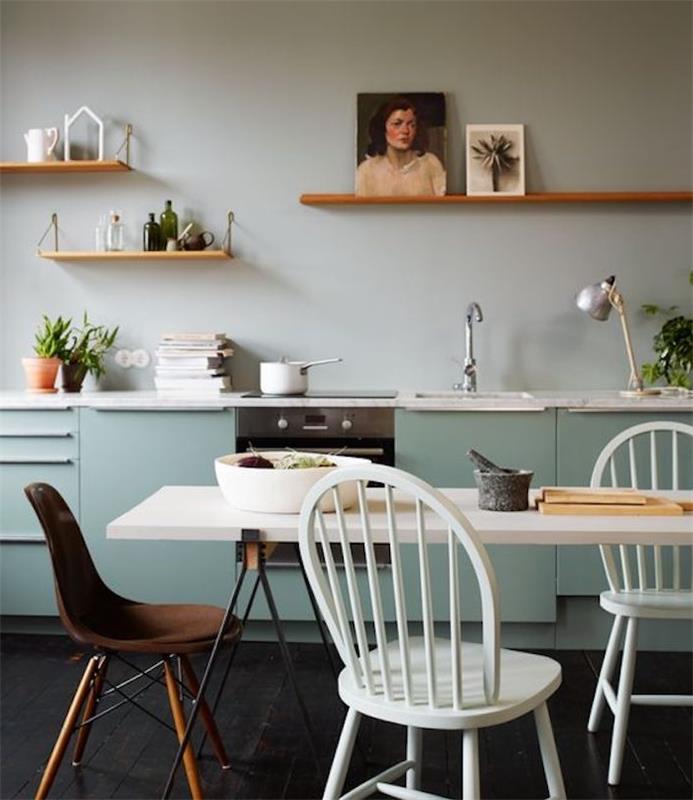 fasada kuhinje v modri barvi celadon, črno -bela jedilna miza, beli stoli in rjavi stol, lesene police