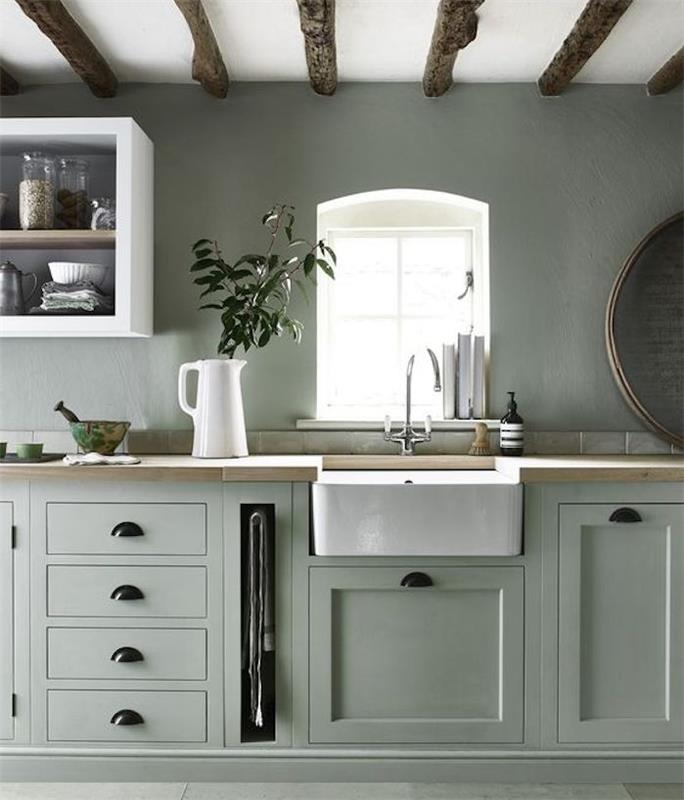 zelena kuhinja celadon z leseno delovno ploščo in belim umivalnikom, bela odprta polica, izpostavljeni tramovi