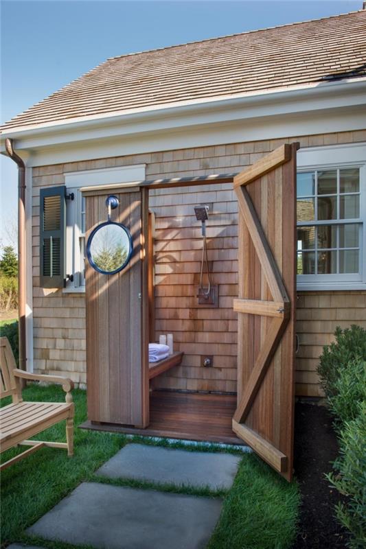ideja, kako okrasiti zunanjo kopalnico z lesenimi vrati in fiksno kovinsko prho, okrogel model ogledala