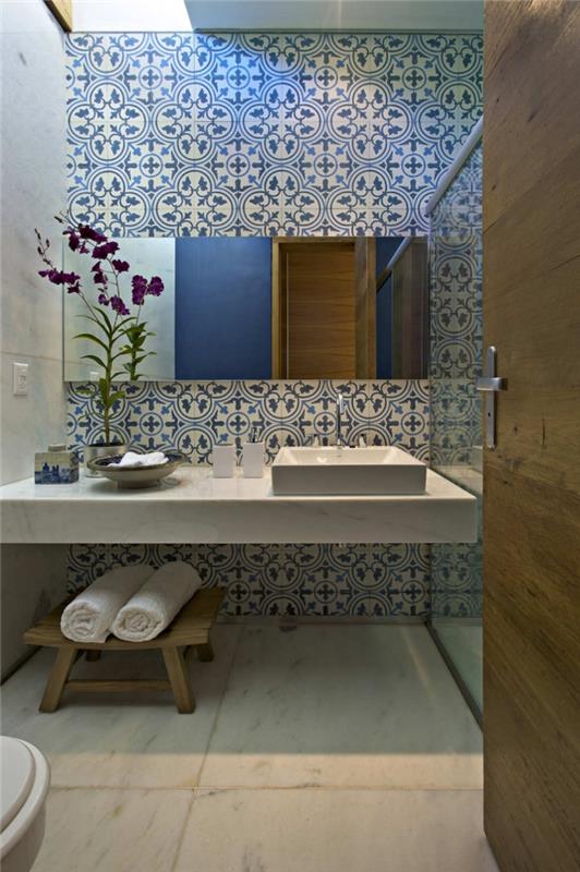 minimalistinio balto marmuro tualeto viršų gražiai paryškina dangaus mėlynos spalvos arabeskiniai vonios cementinių plytelių raštai