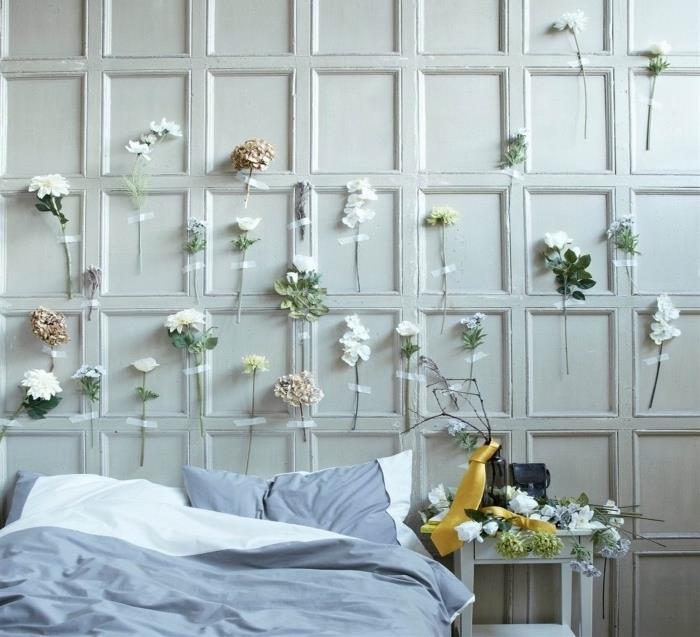 Naglavno glavo, cvetje pritrjeno na steno za posteljo, sivo -belo posteljnino, cvetlični dekor za spalnico