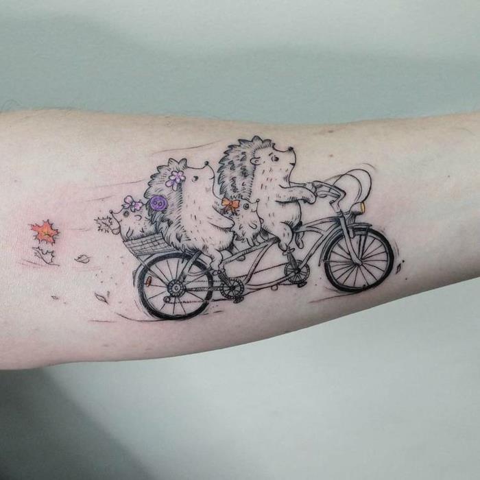 Simpatična stilizirana risbna tetovaža dveh ježkov s svojimi otroki na kolesu, izberite slog njene tetovaže črne in pisane podrobnosti
