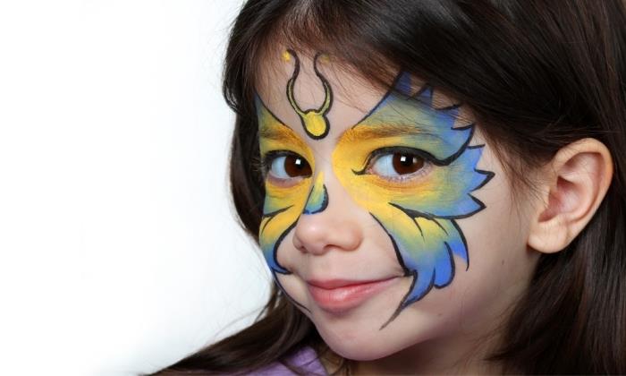 primer lahkega otroškega ličenja s šablono metulja in barvami obraza rumenih in modrih odtenkov z obrisi v črni palici za obraz
