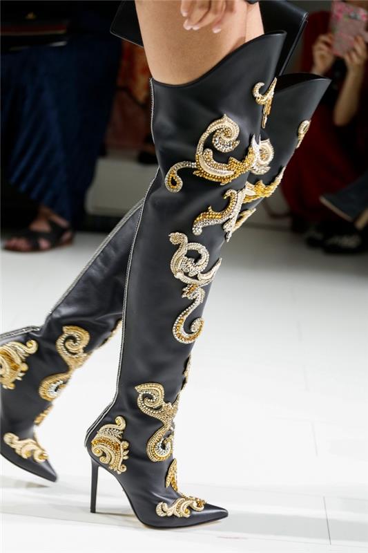 model gležnjarjev z dolžino nad koleni v črni usnjeni izvedbi z okrasjem v zlati in srebrni barvi iz kolekcije Versace