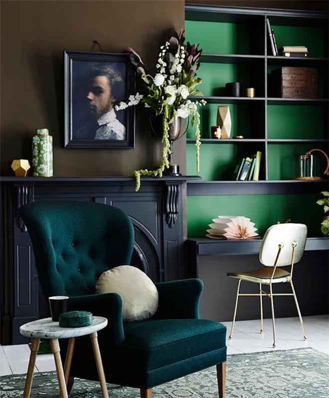 benzininis mėlynas fotelis, pilkas židinys, knygų spinta žaliu fonu, senovinis pilkas ir šviesiai žalias kilimas, portretinis paveikslas su retro rėmeliu