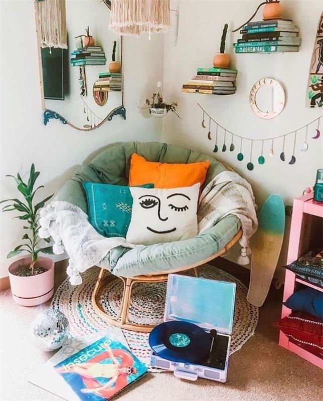 jaukus skaitymo kampelis kokonuojančiame fotelyje, papuoštas spalvingomis pagalvėlėmis, apvalus austas kilimas, plaukiojančios sieninės lentynos su šūsnimis knygų