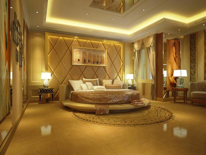 velika okrogla postelja, oblazinjeno vzglavje, lažni strop z razsvetljavo, razkošna spalnica in okrasno stensko dekoracijo