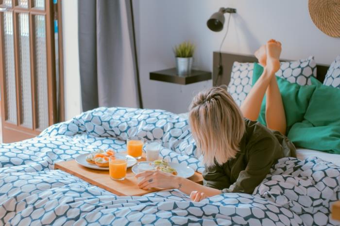Graži mergina ant lovos, sukrečianti pusryčių akimirką lovoje, nuotrauka, naudojama kaip jos tapetai