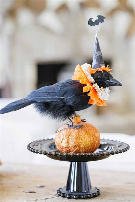 siyah düz taban üzerinde siyah yapay kuş heykelcik ve küçük turuncu balkabağı ile dekoratif Halloween aksesuarı