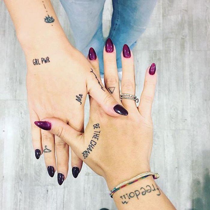 dve dekleti, s številnimi tetovažami, vijoličnim in črnim lakom za nohte, tetovaža s prekrižanimi prsti, srebrni prstani