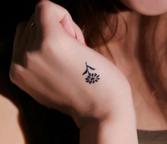 fiore-tattoo-piccola-margherita-stilizzata-nera-foglie-gambo-lato-mano-ragazza