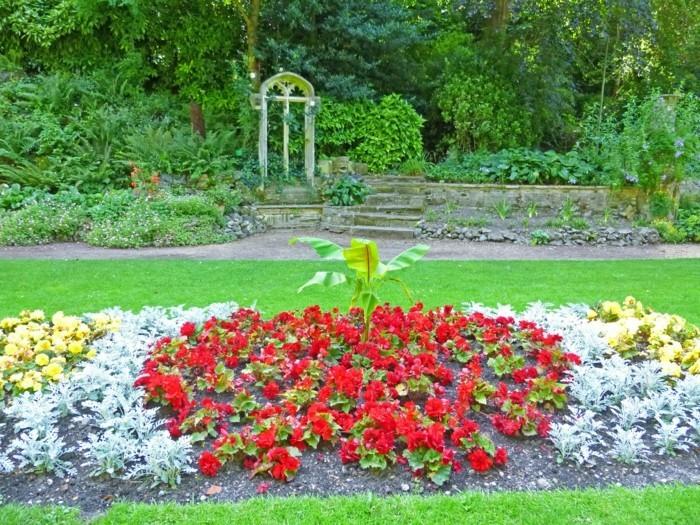 çiçeklerle dolu bir çiçeklik, kırmızı, sarı ve yeşil çiçekler, çimenlikte, estetik bir bahçe için harika bir fikir