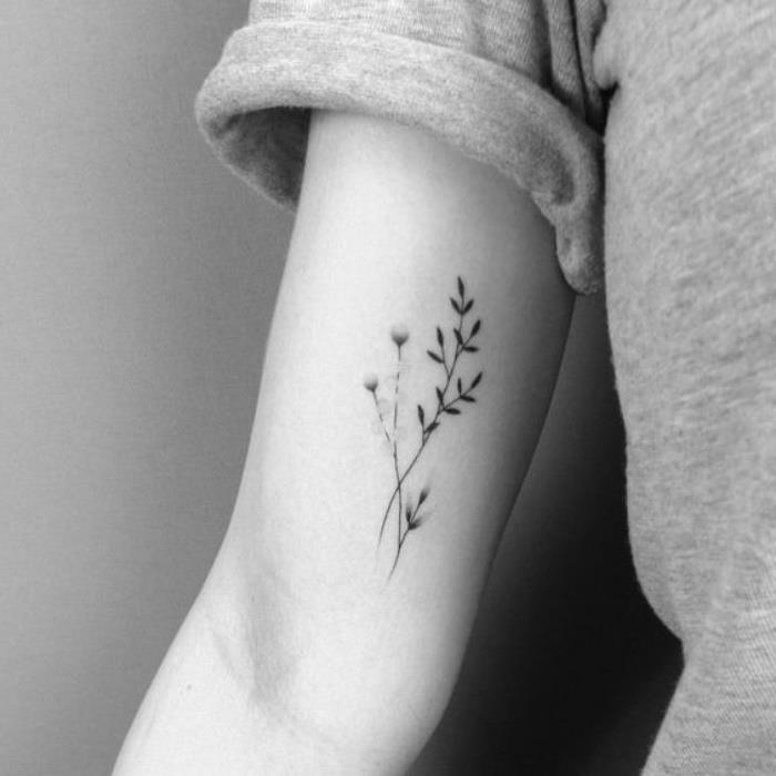 mažos tatuiruotės su prasme, gėlių tatuiruotė rankos viduje, žmogus, vilkintis pilkus marškinėlius