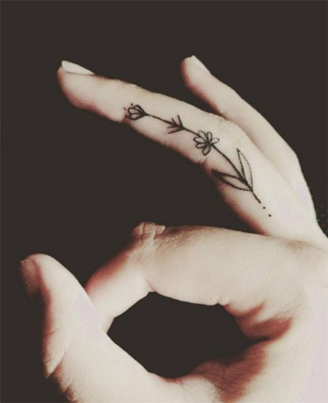 tetovaže majhnih rož, tetovaža srednjih prstov, tetovaža s prekrižanimi prsti, roka pred črnim ozadjem