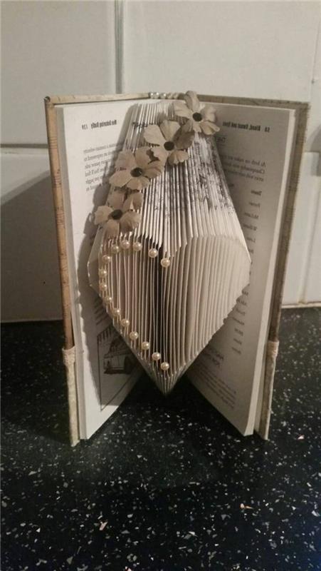 zložena knjižna umetnost, oblika srca iz prepognjenih strani, okrašena z belimi bisernimi kroglicami, in papirnato cvetje, znotraj odprte knjige, s trdimi platnicami