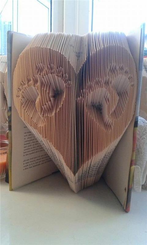 zloženi knjižni umetniški vzorci, dva niza majhnih odtisov otroških stopal, znotraj oblike srca, narejeno iz prepognjenih strani, znotraj odprte knjige