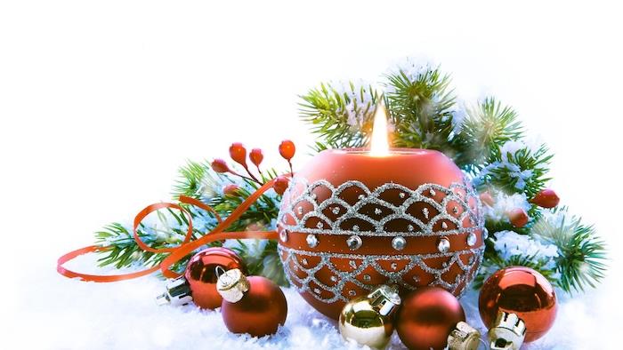 Kalėdų fonas raudonai rudoje dekoratyvinėje žvakėje, sidabro rašto dekoracijos, raudoni ir auksiniai Kalėdų rutuliai, pušies šakos, dirbtinis sniegas