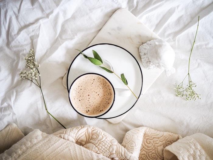 bitki dalları ve yorganlar ile yatakta bir fincan kahve ile nötr ve minimalist duvar kağıdı