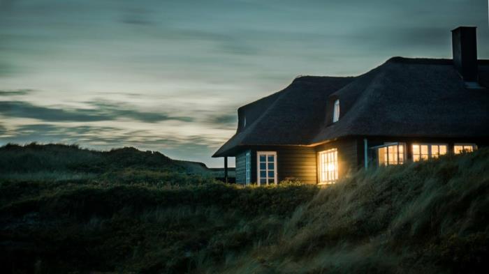 amerikietiško stiliaus namas pievoje, žalių atspalvių dangus, labai aukšta žolė, paslaptingai apšviesti langai, rojaus kraštovaizdis