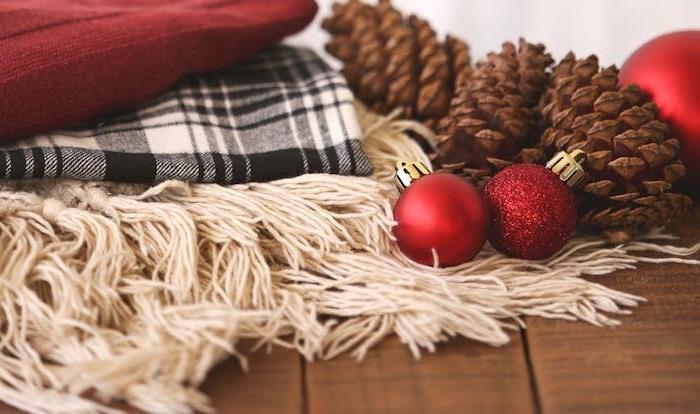 Kalėdinių tapetų pavyzdys, baltos, raudonos ir juodos spalvos antklodės, raudoni Kalėdų rutuliai ir kankorėžiai