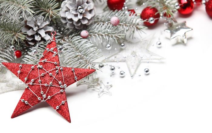 Kalėdų fonas raudonoje žvaigždėje, papuoštas sidabrinių perlų girlianda, apsnigtomis pušies šakomis, kankorėžiais ir Kalėdų kamuoliukais