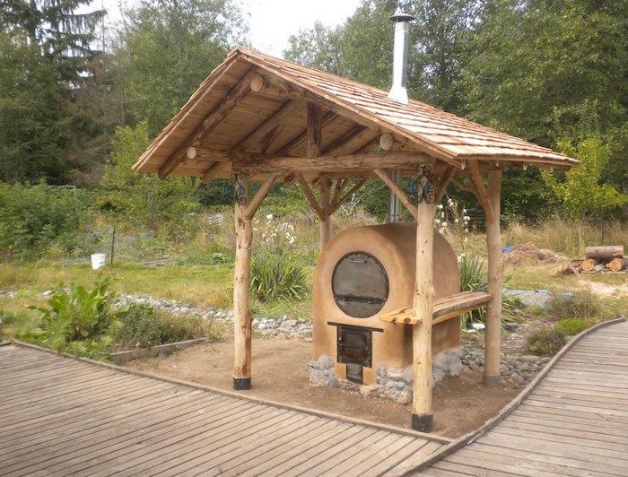 ahşap bir çatı altında odun yanan beton fırınlı küçük bir bahçe mutfağı modeli