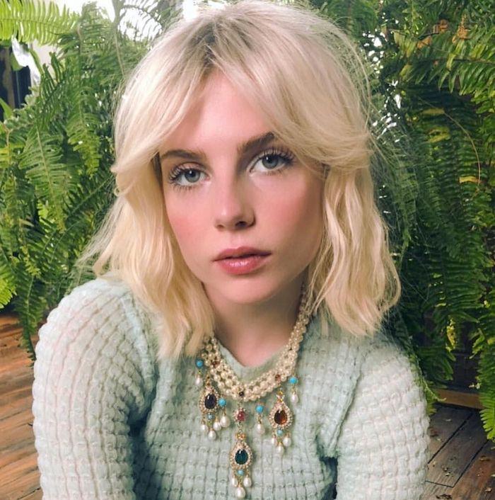 bardot, okul çocukları giyen örme bir bluz giymiş yeşil bitkilerin önünde sarışın bir kadına vuruyor