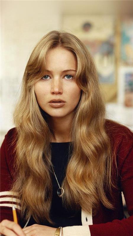 Igralka Jennifer Lawrence z dolgimi zavesami je z blond lasmi in peresom v roki