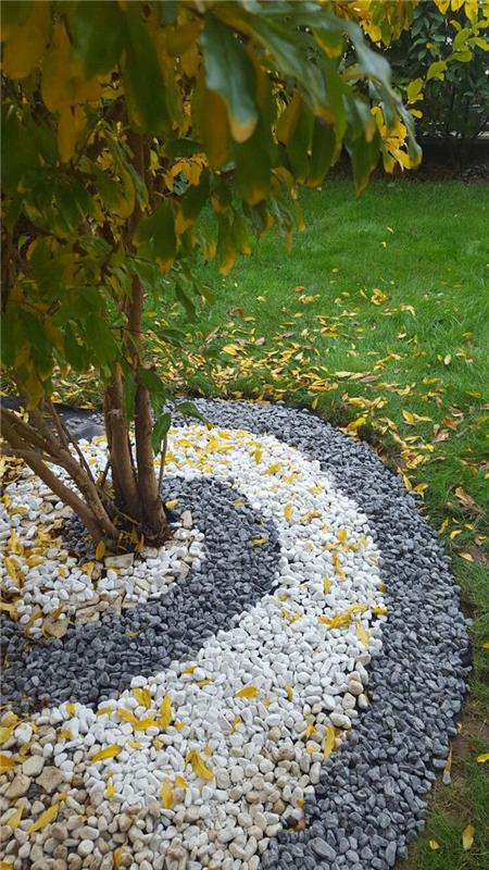 gredica, zelena trava, pokrita z oranžnimi in rumenimi listi, vrtna dekoracija v belih in črnih kamenčkih
