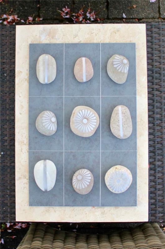 kamenčki, okrašeni s srebrno barvo za uporabo v improvizirani igri z nulami in križi