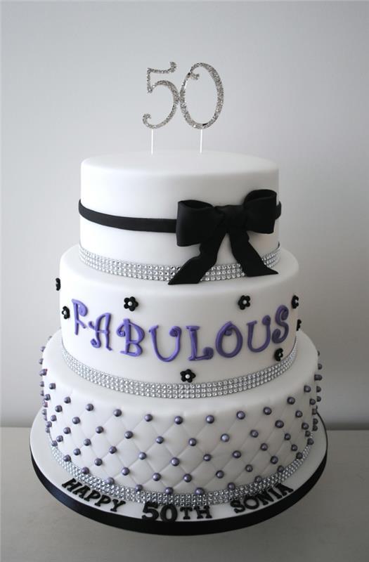 puošnus baltas suaugusiųjų gimtadienio tortas, juoda juostelė, suformuota pasta ir raštais