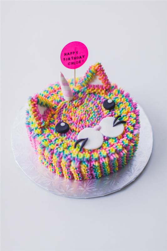 mavrična torta v obliki glave mačke, okrašena z majhnimi večbarvnimi cvetovi v glazuri