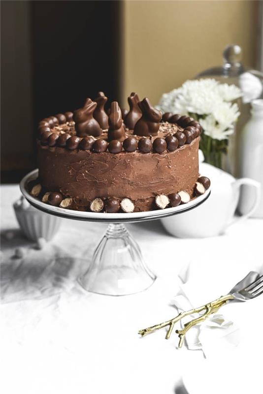 enostavna in okusna čokoladna velikonočna torta, mehka torta, prekrita z masleno kremo in čokoladno glazuro, z velikonočno tematsko dekoracijo malih čokoladnih zajčkov