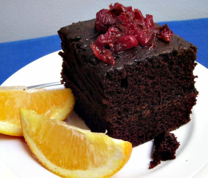 šokoladinis pyragas be kiaušinio, raudonos vyšnios ant viršaus ir dvi citrinos skiltelės