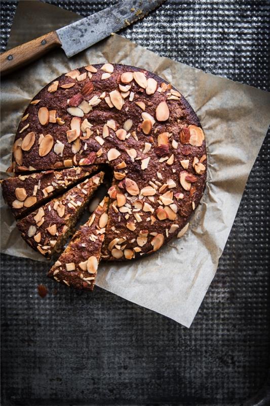 Bir fırın kağıdına yerleştirilmiş, üzerine kavrulmuş kuşbaşı badem serpilmiş glutensiz badem ve limonlu kek için hızlı ve kolay tarif