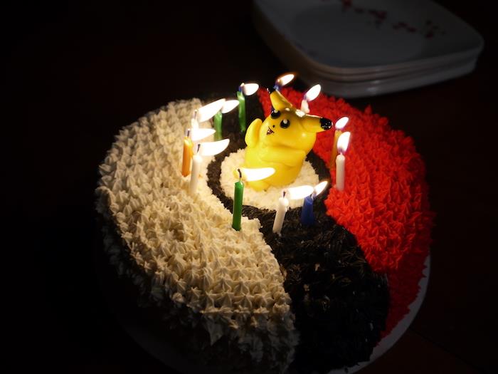 pokemon torta, plastična figura pikachu, rojstnodnevne sveče, bela krema, pokemon ball