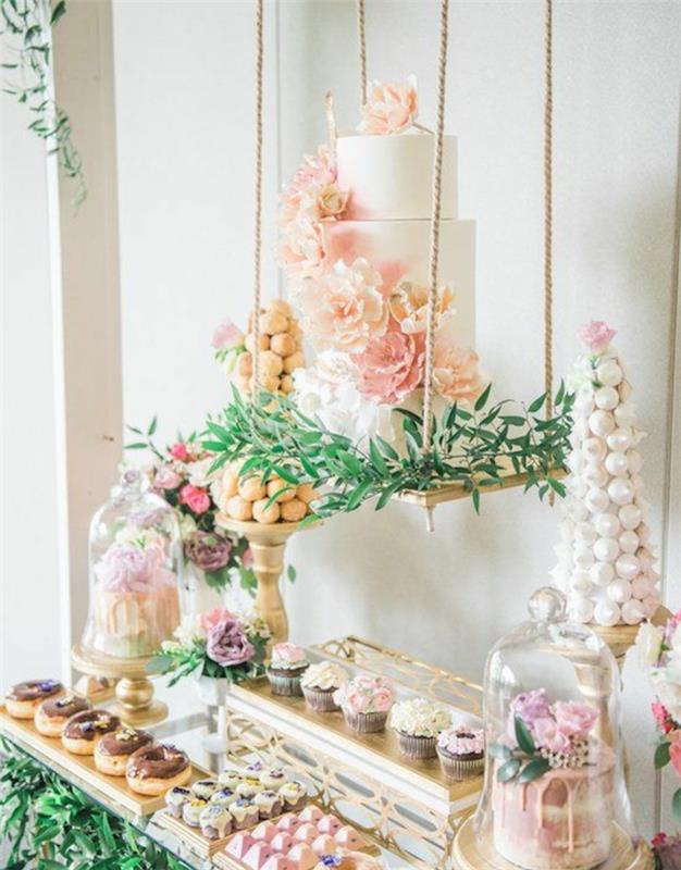 poročna torta, okrašena s cvetjem na gugalnici, piškoti, krofi, majhne torte, meringue, bonboni, okras cvetličnega šopka in zelenih vej, poročna sladkarija