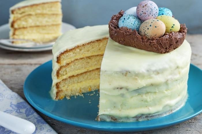 Velikonočna gnezdeča torta iz vanilijeve biskvitne torte, napolnjene s smetano, prekrite z belo glazuro z majhnim čokoladnim gnezdom