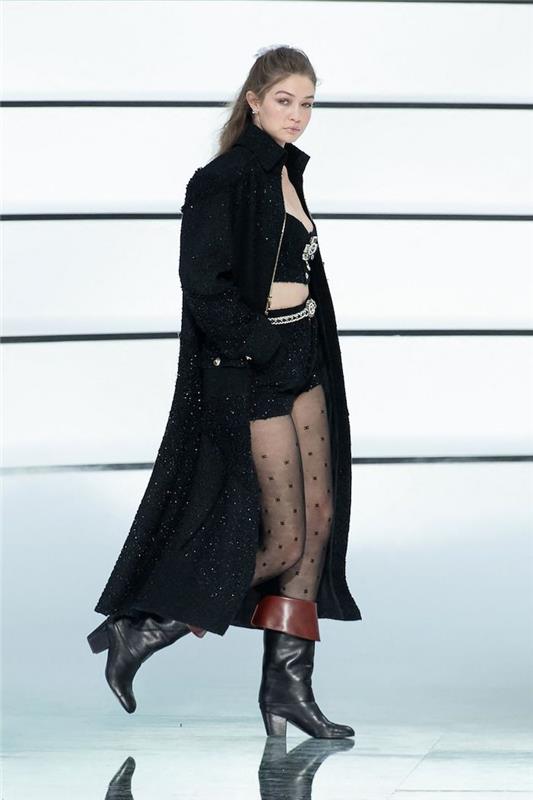 gigi hadid Chanel, apsirengusi per dideliu paltu, trumpi viršutiniai šortai ir pėdkelnės atsitiktine elegantiška apranga