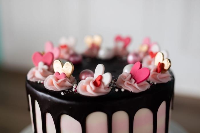 pembe kremada yenilebilir kalpler ve mini çiçeklerle romantik bir bitter çikolatalı pastayı nasıl süsleyeceğinize bir örnek
