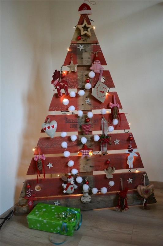 Kalėdų eglutė iš medinių lentų, trikampio formos su padėklais, pomponų girlianda, elniai, širdys ir žvaigždės, mažos tekstilės figūros