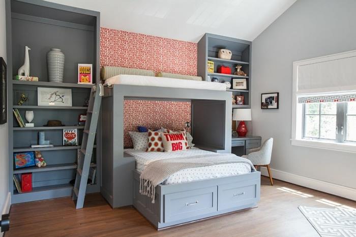 dvojna otroška postelja, sive knjižice, rdeče ozadje, majhna siva miza, lesena tla