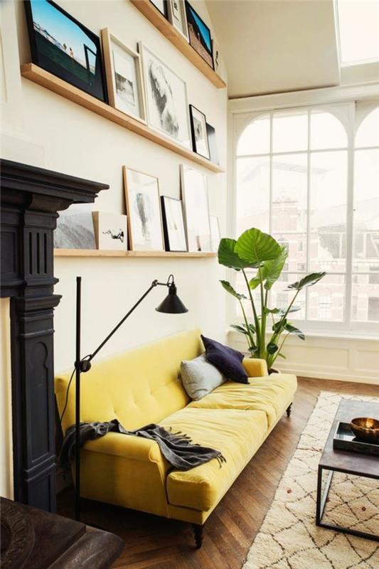 didelė sofa-svetainė-geltona-smėlio spalvos kilimas-parketas-tamsiai-medžio-žalia-augalai-interjerui