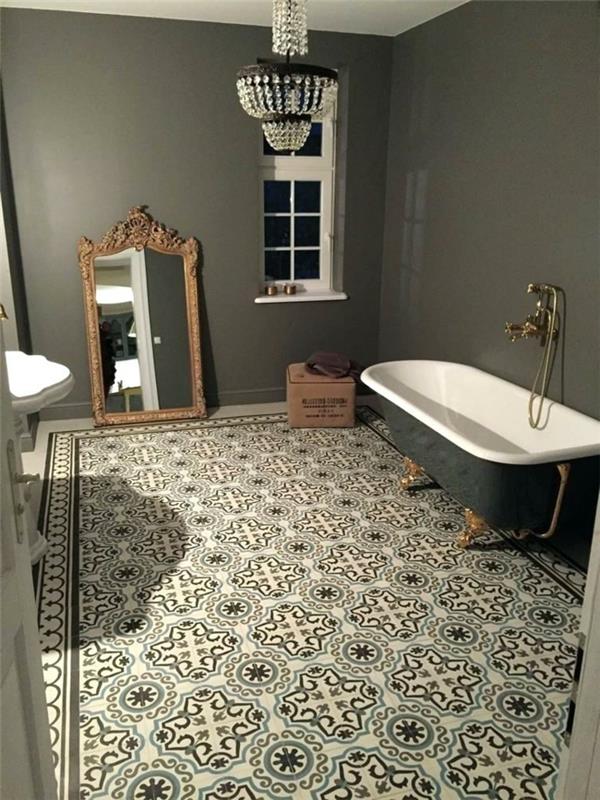 banyo zemininde gri ve beyaz çimento karolar, barok çerçeveli ayna, dökme demir küvet ve duvar musluğu, oryantal tavan lambası