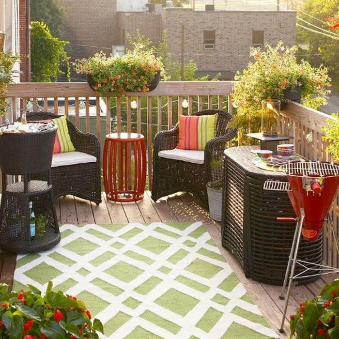 kahverengi hasır mobilya seti, iki sandalye ve bir masa, buzlu şarap soğutucusu, daha küçük kırmızı metal masa ve aynı renkte ızgara, dış mekan veranda fikirleri, yeşil ve beyaz kilim ve saksı bitkileri